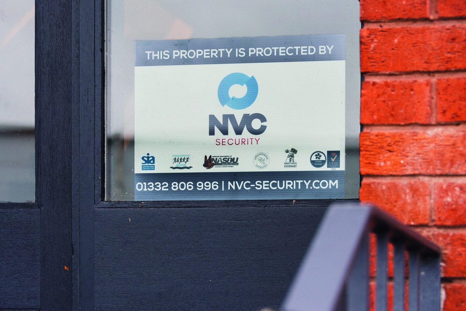 NVC protected-by sign fixed to a site fence